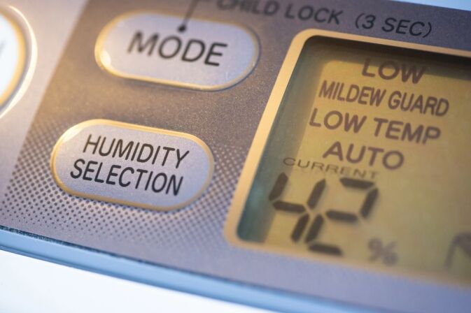 Close-up of a digital humidity control panel displaying Humidity Selection button and a screen showing current humidity at 42% with various mode options.