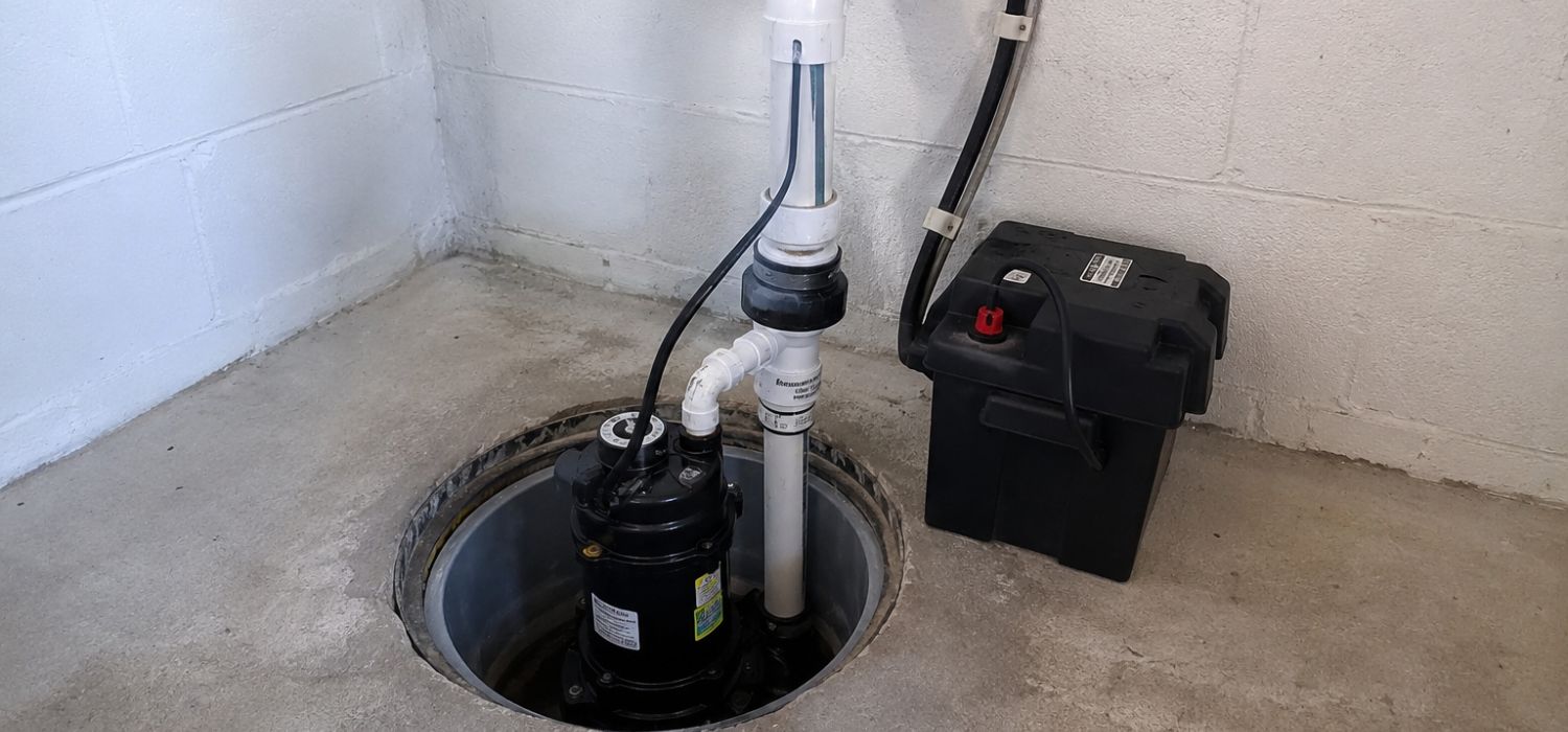 A professional sump pump installation in Springfield, MO, featuring a basement sump pit with drainage piping and battery backup system.